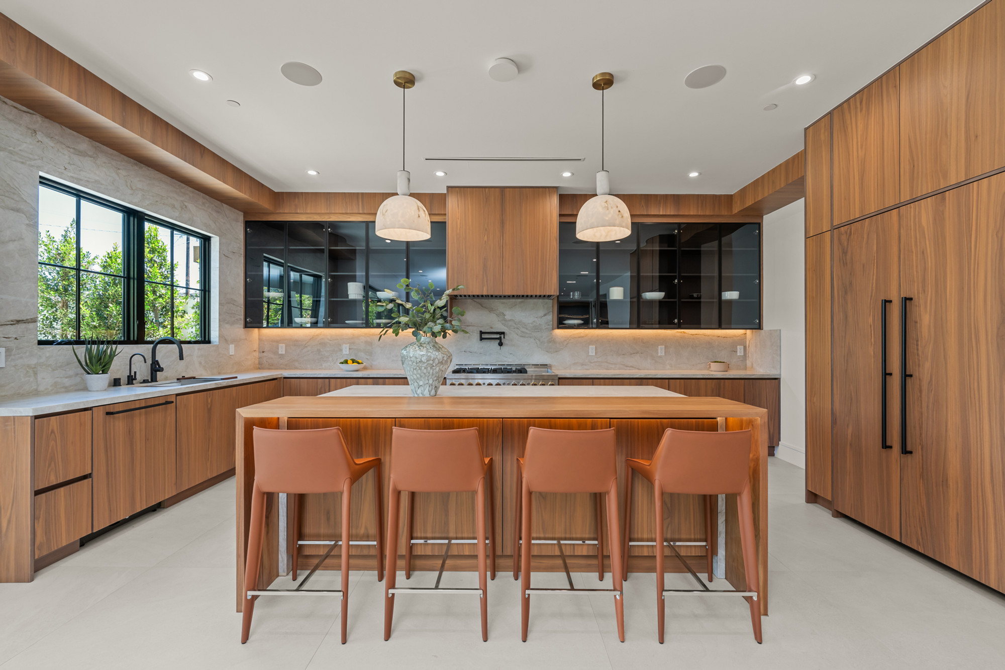 Walnut kitchen with honed marble and brass pendants